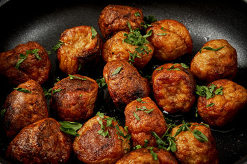 delicious meatballs with parsley in a pan on a black old wooden table