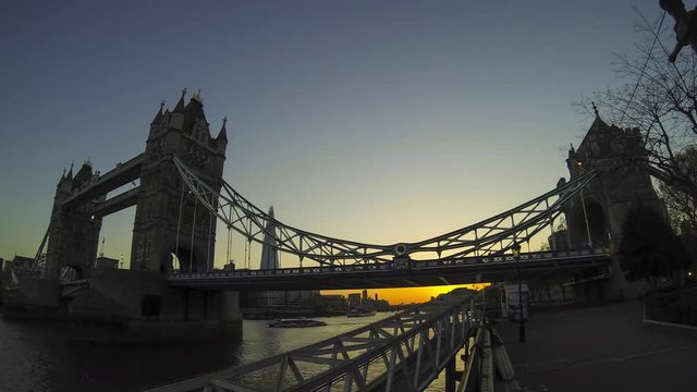 Time lapse footage at sunset with the famous Tower Bridge and the Girl and Dolphin statue in St Katharine docks, London, UK. Tourists taking pictures. Wide angle lens.