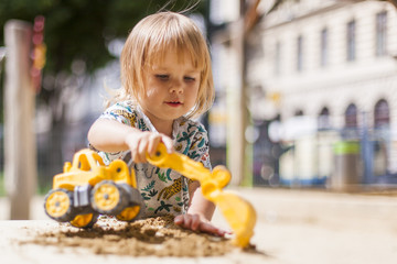 Little girl, child playing with digger in sand. Kleines Mädchen, Kind spielt mit Bagger in Sand. 