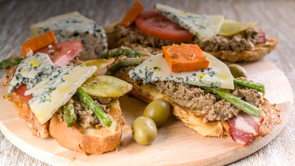 Fototapeta na wymiar Italian sandwiches with mushroom pate, vegetables and cheese. Mediterranean traditional cuisine. Close-up