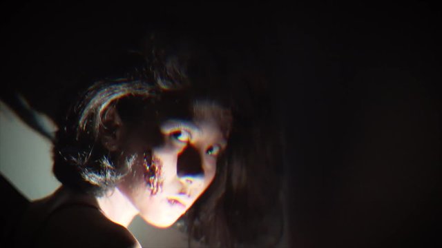 Scary wounded zombie woman looking at the camera in dark at home, shot in 4k resolution