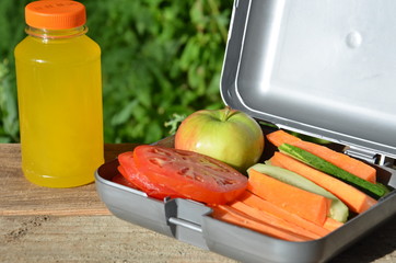 Lunch boxes with food ready to go for work or school, meal preparation or dieting concept. Hamburgers with lettuce. yellow orange juice. with banana nuts. Sliced vegetables carrots and cucumber