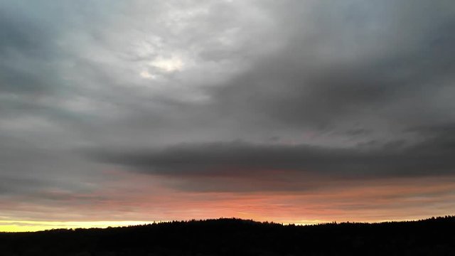 Vue a&eacute;rienne sur un coucher de soleil gris et orange au dessus des montagnes apr&egrave;s un orage 