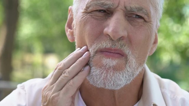 Retired man suffering from toothache, discomfort with implants, dental care
