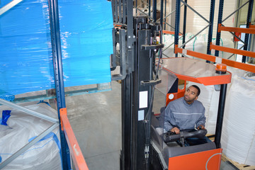 Forklift driver stacking pallet high in racking