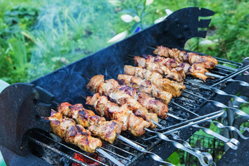 cooking homemade barbecue on charcoals grill in summer garden 