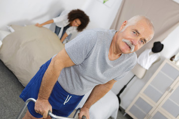 senior male patient using walker at rehab center