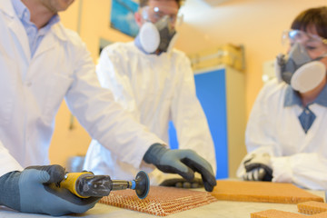 People wearing protective masks as man uses small grinder