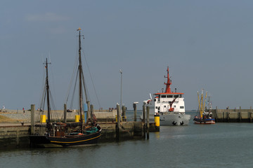 Naklejka premium Boot und Fähre und Ausflugskutter im Sielhafen Neuharlingersiel im Weltnaturerbe Nationalpark Wattenmeer - Stockfoto