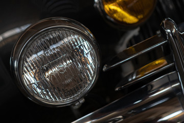 The headlight of an antique, rarity, vintage black car.