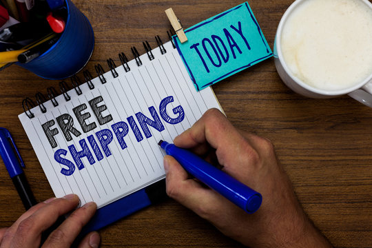 Text sign showing Free Shipping. Conceptual photo Freight Cargo Consignment Lading Payload Dispatch Cartage Man holding marker notebook clothespin reminder wooden table cup coffee