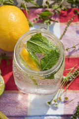 Cold refreshing drink in glass jar with slices of lemons and limes.
