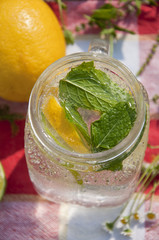 Cold refreshing drink in glass jar with slices of lemons and limes.