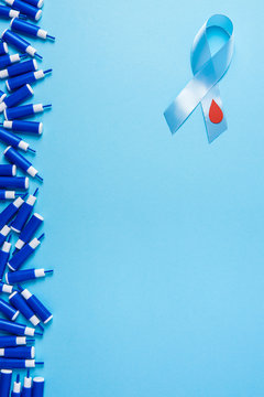 blue ribbon awareness with red blood drop and line of lancets on a blue background, World diabetes day