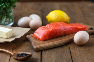 Raw salmon pieces on wooden board with herbs, salt and spices