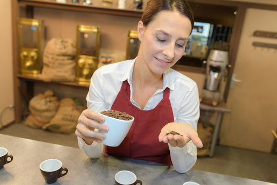 female worker holding coffee beans in a coffee shop