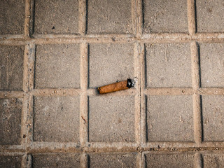 Above view of cuban cigar stub on gray concrete pavement