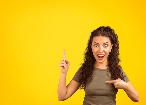 Excited woman in surprise pointing at herself