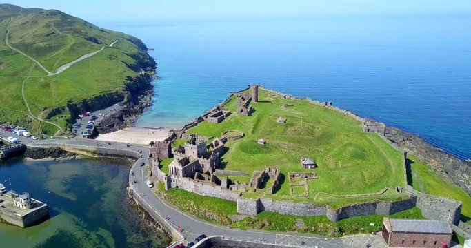 Drone flying over Peel Castle on Isle of Man, landmark building in Peel on the Isle of Man, originally built by Vikings. Aerial view of beautiful sea village with old monument seen from the sky