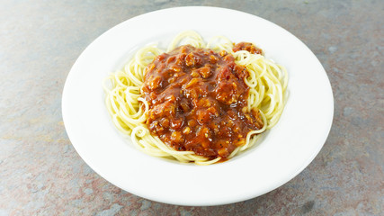 Spaghetti bolognese with tomato sauce and meat in a dish White on a wood floor table, Top view with copy space for your text.