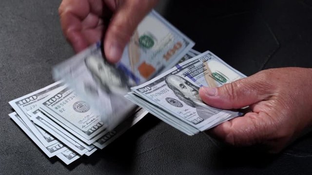 Counting US currency. Old woman counts money. New dollars in hands with wrinkles. Close up view. Business, finance, savings concept. Slow motion.