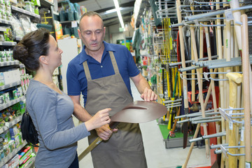 mature happy seller smiling at gardening section of household store