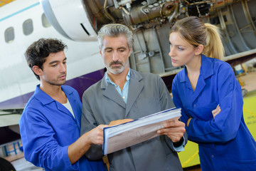 Obraz premium People in aircraft hangar looking at paperwork