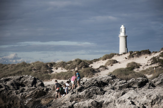 ROTTNEST ISLAND, AUSTRALIA : MAY 31 2013 - The Bathurst Lighthouse At The Background With Kids Playing At The Seaside