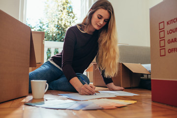 Woman sitting on floor and writing on paper