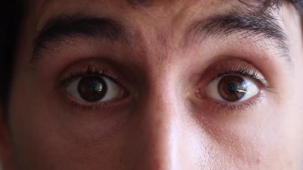 Man closes eyes and opens them back again. Young man with a suprise look on his face. 30 year old man looking at camera