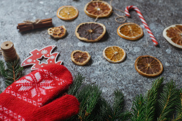 Christmas or New Year flat lay home decor, dry oranges, cinnamon, candies and fir branches on concrete background. Cozy winter homely scene, top view