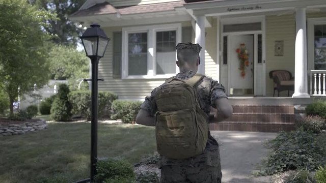 Soldier walking up to house in slow motion