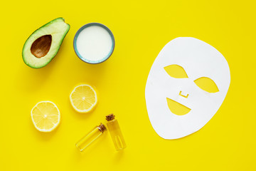 Skin care. Facial mask, cream and lotion near avocado and lemon on yellow background top view