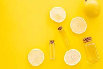 Obraz na płótnie Canvas Natural cosmetics. Lemon essential oil near halfs os lemons on yellow background top view closeup copy space