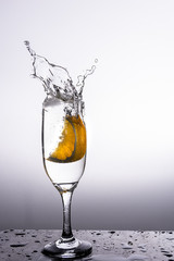 Glass of liquid with splash made dropping a slice of orange