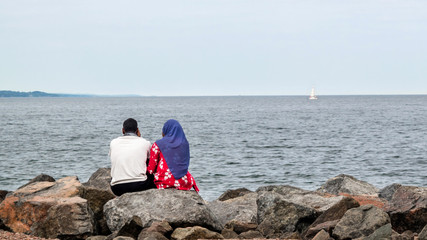 A Muslim couple are sitting on a rock to look at Lake Superior