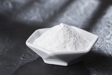 baking soda in bowl on wooden table, close up