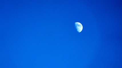 Moon in clear blue sky at morning time