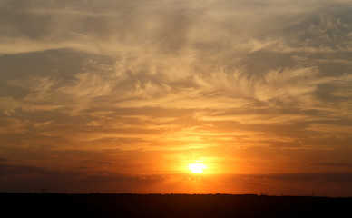 Beautiful photo of a bright sunset with clouds over a field