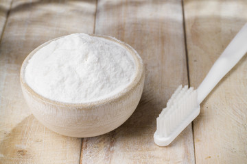 baking soda in bowl on wooden table, close up