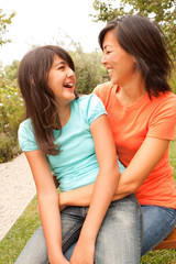 Naklejka premium Asian mother and her daughters hugging and laughing.