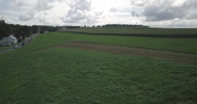 The drone films green, cultivated farmland while it descents. On the left side some cars are driving on a road, which leads to Schnecksville, Pennsylvania
