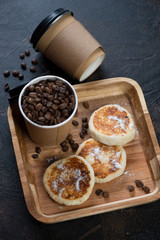 Takeaway coffee and cottage cheese pancakes on a wooden serving tray, vertical shot, elevated view