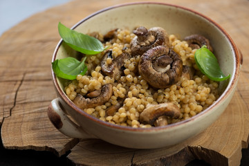 Pasta with cep boletus and champignons served in a bowl in a rustic wooden setting, selective focus