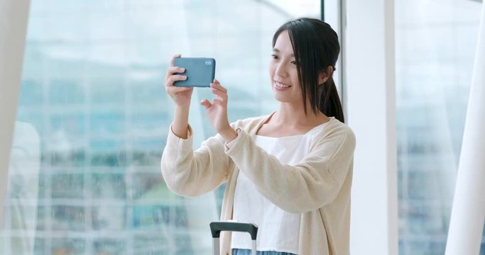 Woman taking photo on cellphone in the airport