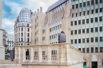 Naklejka premium Man sitting on a stony enclosure surrounded by the architecture of the city