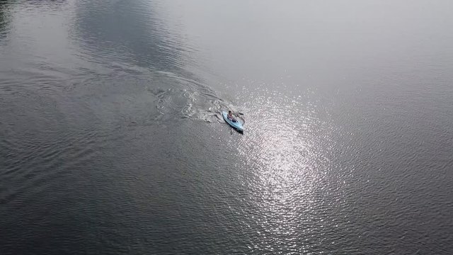Drone aerial view of a man kayaking in a calm lake.