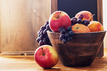 Apples and dark grape in wooden bowl.