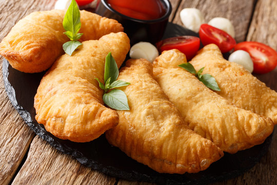 Italian pastries: deep-fried pancerotto with tomato sauce and mozzarella close-up on a black board. horizontal