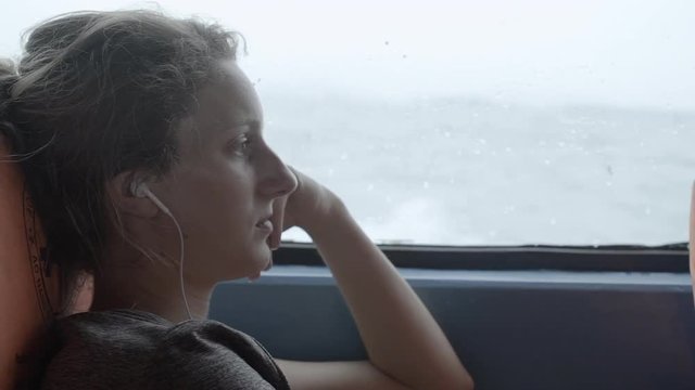 A young woman listens to music while riding in a boat.